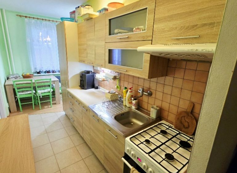 Kuchyně ve 4-pokojovém bytě s dřevěným dekorem a jídelním koutem.