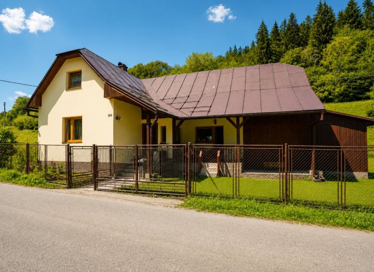 Chata na ulici Černé v Makově s okrasným trávníkem a dřevěným plotem.