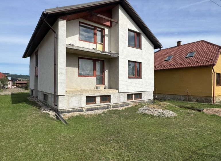 Rodinný dům v Plavnici se zeleným trávníkem a částečně dokončenou fasádou.