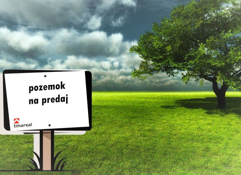 Tabule oznamuje prodej pozemku, zobrazený je zelený trávník vedle stromu.