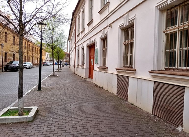 Ulice Františkánská v Trnavě s historickými budovami a stromy u kanceláří.