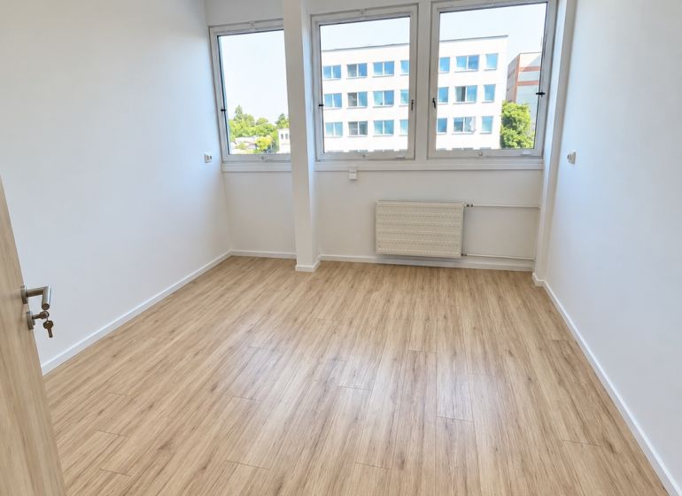 Kancelář s podlahou s dřevěným dekorem, interiér s velkými okny a stropním osvětlením.