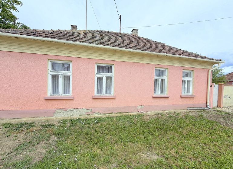 Rodinný dům v Dunakiliti s růžovou fasádou a čtyřmi okny v přízemí.