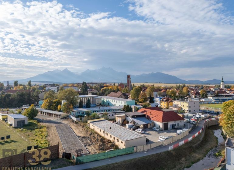 Panorama Kežmarku s garážemi, pohled na blízké Tatry a rozmanitou architekturu města.