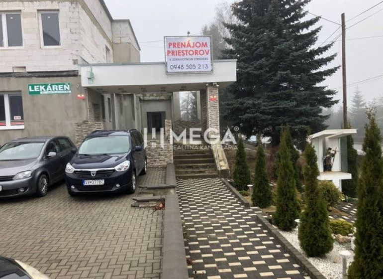 Budova na ulici SNP v Snině s parkovištěm a reklamou na pronájem prostor.