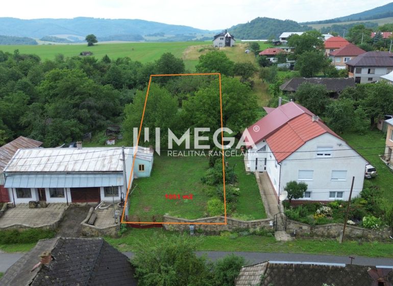 Pozemek v Oľšinkově vhodný k bydlení, obklopený zelení a nedalekými domy.