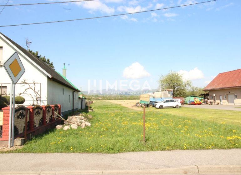 Pozemky - bydlení v Sačurově s domy, trávníkem a dopravní značkou.