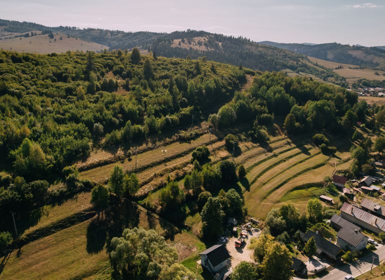 Letecký pohled na zelené kopce a domy na Školní ulici v Černém Balogu.