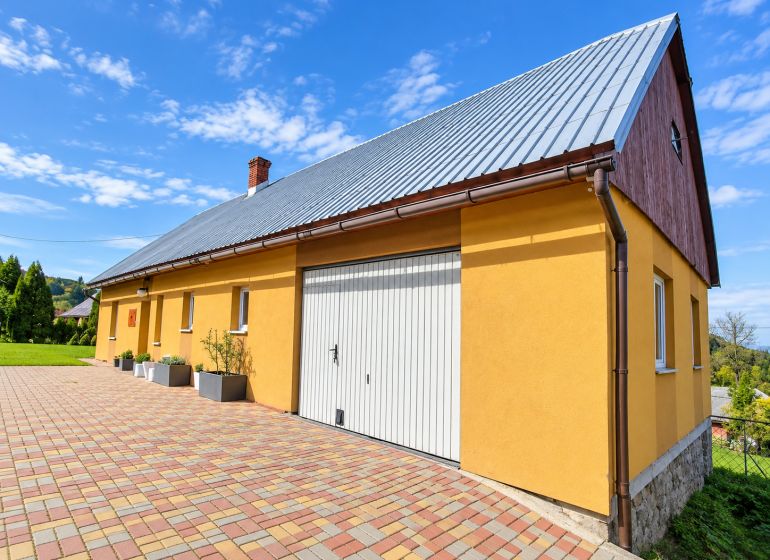 Žlutý rodinný dům na ulici Košariská v Oščadnici s pestrobarevnou dlažbou.