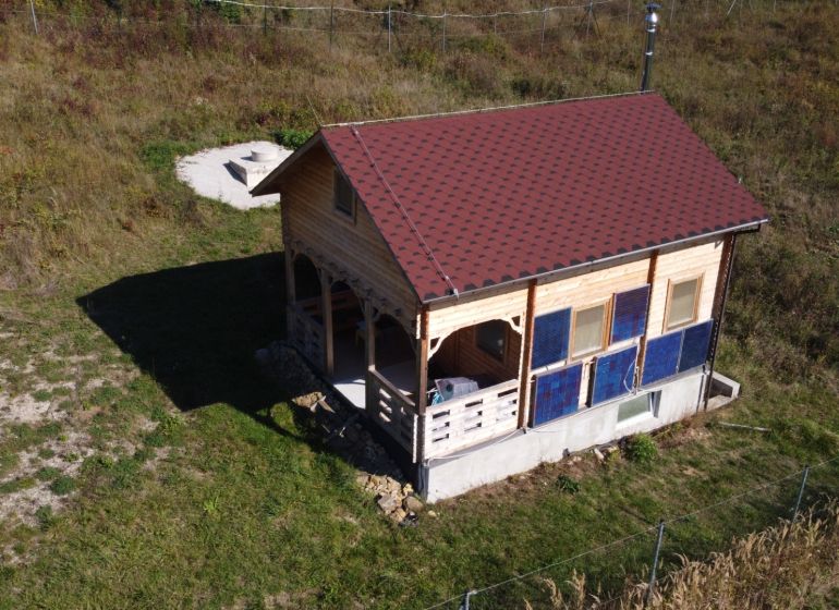 Chata v Horní Breznici s dřevěným obkladem a červenou střechou na zeleném pozemku.