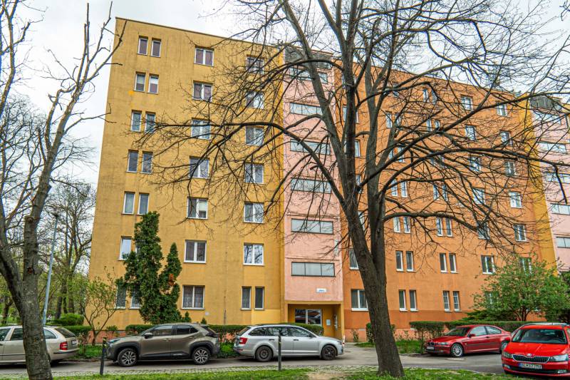 Pekný bytový dom na ulici Zimná s 3-izbovými bytmi, obklopený stromami a autami.