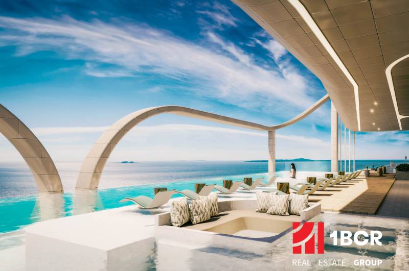 Luxusní bazénová terasa s lehátky a výhledem na oceán v rámci výstavby bytů.