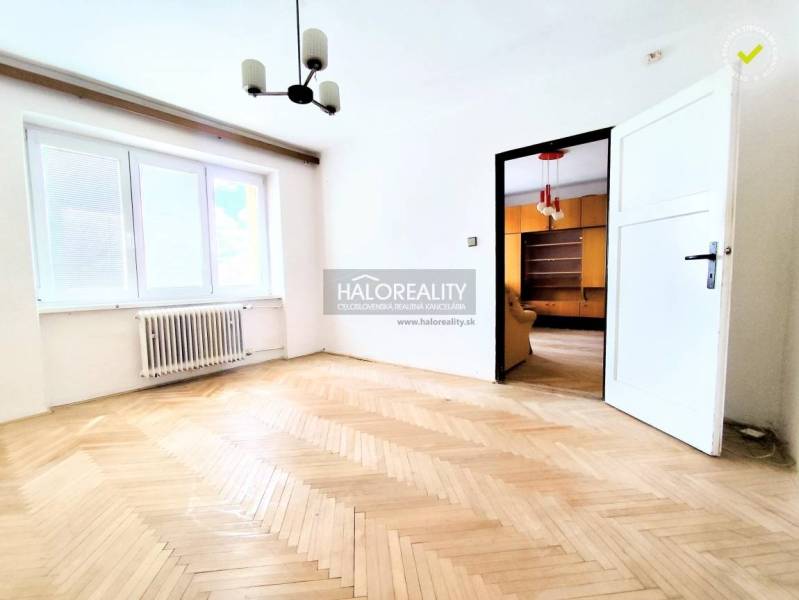 Světlý pokoj s parketami a bílým nábytkem pravděpodobně v 2-pokojovém bytě.