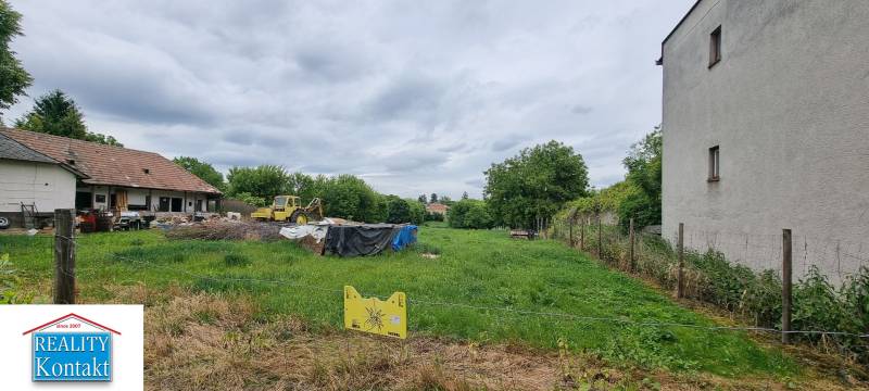 Pozemky - bydlení v Dubníku, travnatá plocha s budovami a strojem, oplocené plotem.
