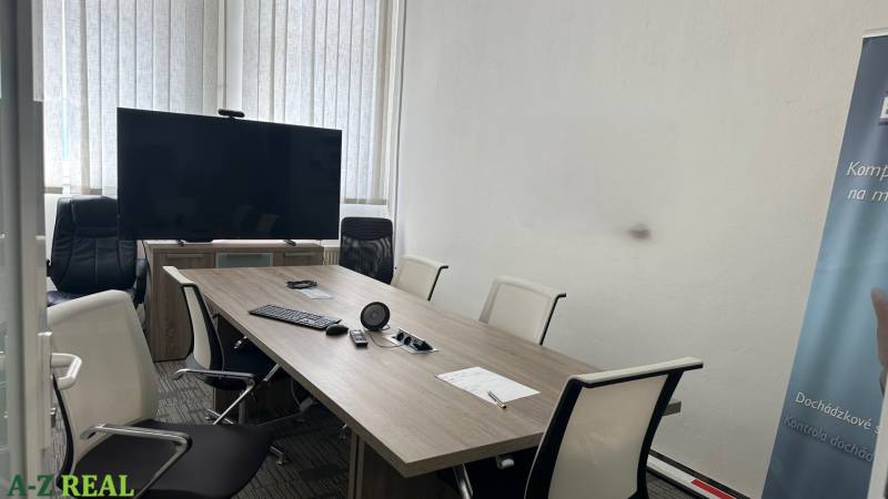 Kanceláře se zasedací místností, stolem, židlemi, televizorem a projektorem na prezentace.