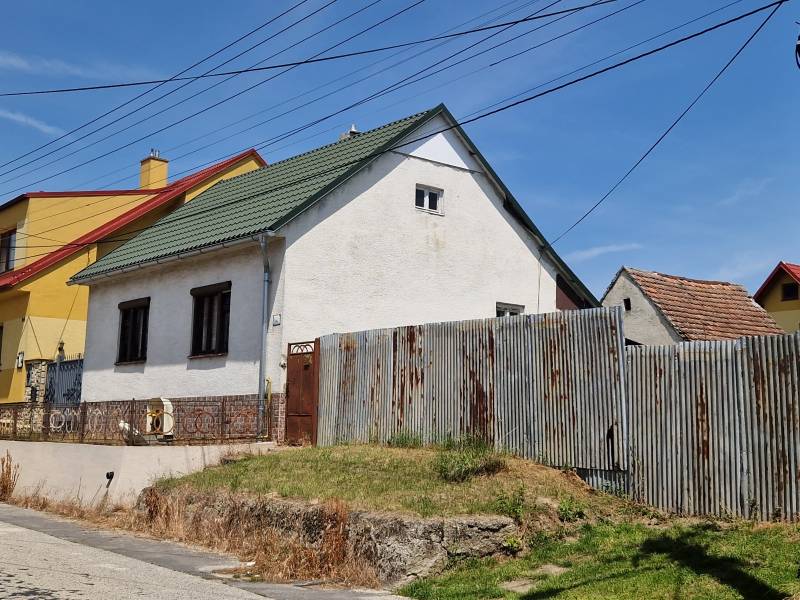 Rodinný dům ve Štefanově s plechovým plotem a šikmou střechou pod modrou oblohou.