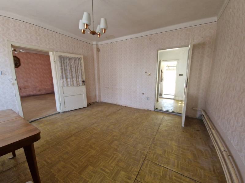 Interiér rodinného domu s dřevěnou podlahou, tapetami a závěsy na dveřích.