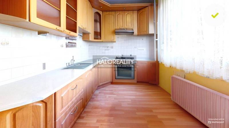 Kuchyně s dřevěnou linkou a spotřebiči v 3-pokojovém bytě, světlé dlaždice, záclony.