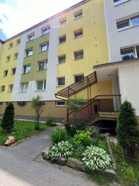 Bytový dům na Tulskou ulici v Banské Bystrici s barevnou fasádou a záhonem.
