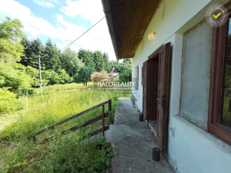 Chata ve Staré Huti obklopená zelení a lesy, s otevřenými dveřmi do přírody.