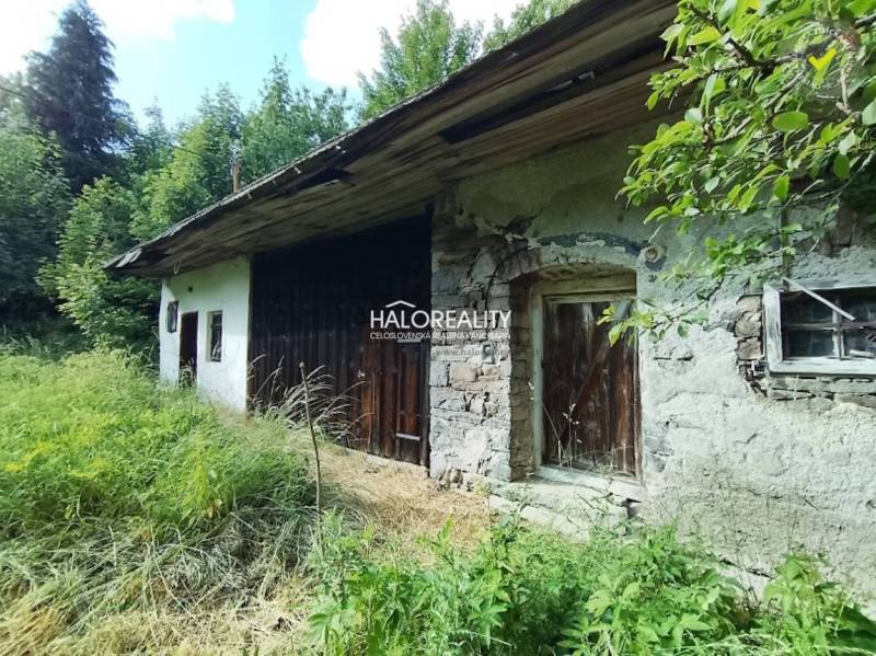 Chata ve Staré Huti obklopená zelení s dřevěnými prvky a kamennými stěnami.