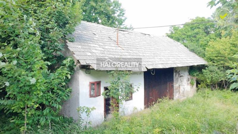 Chata ve Staré Huti obklopená zelení, se šikmou střechou a dřevěnými prvky.