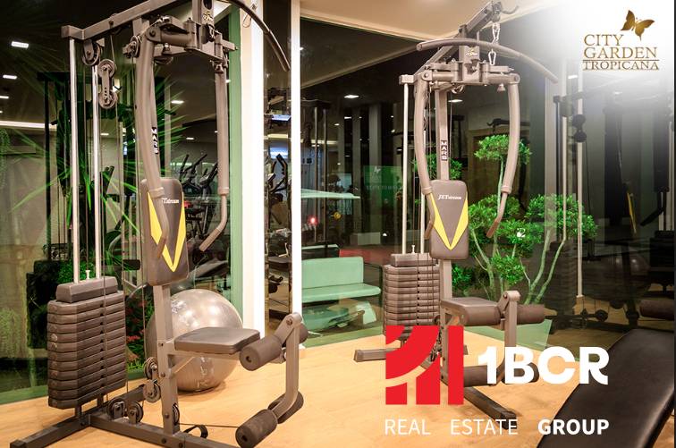 Fitness vybavení ve výstavbě bytů, zelené prvky, osvětlení a zrcadlové stěny.