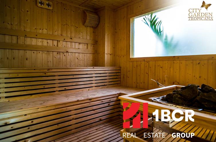 Dřevěná sauna s proskleným oknem a logem realitní kanceláře.