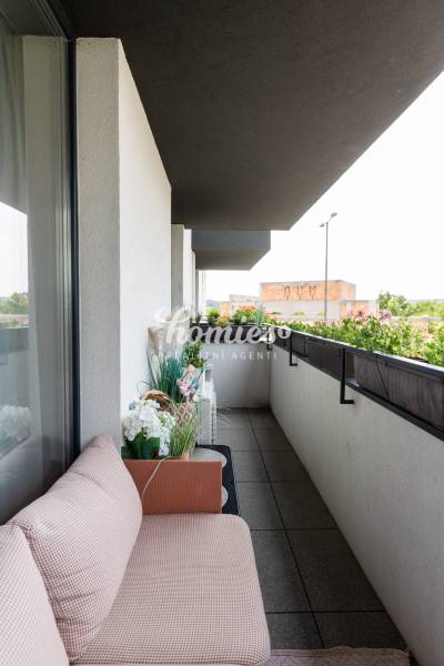 Balkon s posezením a květinami v 2-pokojovém bytě.