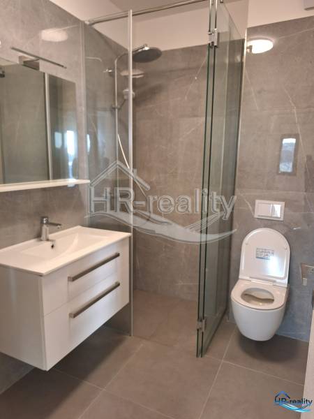 Koupelna v rekreačním apartmánu s moderní sprchou a zrcadlem.