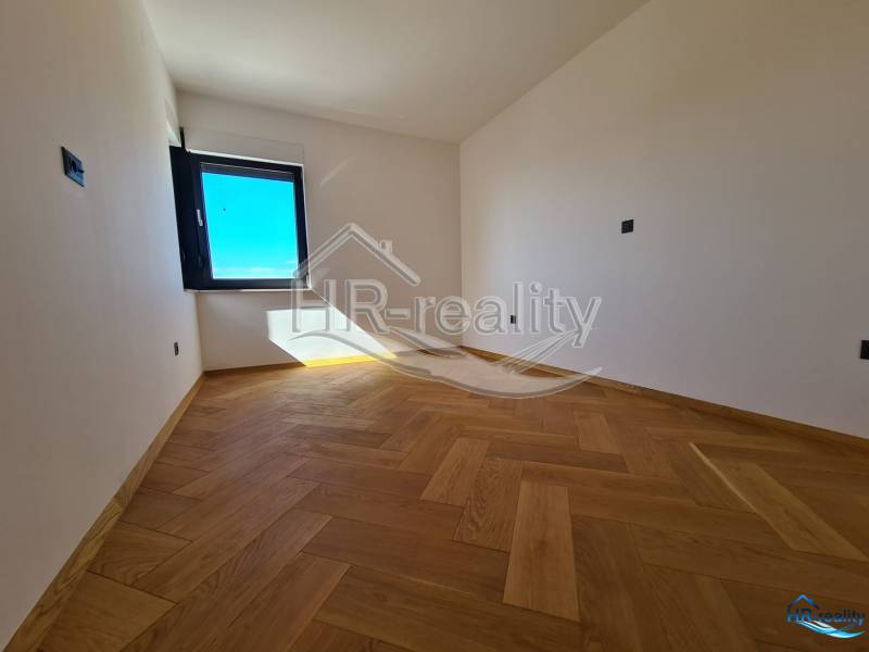 Prostor s dřevěnou podlahou a velkým oknem v rekreačním apartmánu.