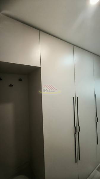 Bílé skříně s vertikálními úchyty v garsonce.
