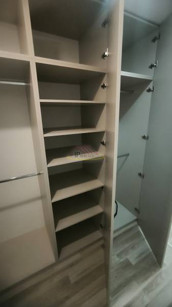 Vestavěná skříň se zásuvkami a poličkami v garsonce, podlaha ze dřeva.