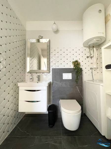 Koupelna v rekreačním apartmánu s úložným prostorem, zrcadlem a pračkou.