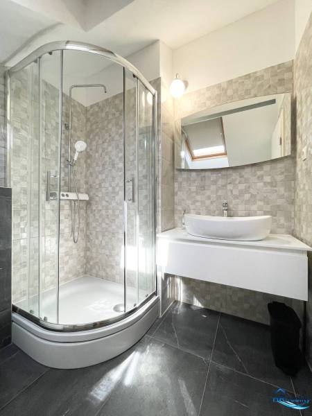 Koupelna v rekreačním apartmánu s moderním sprchovým koutem a umyvadlem.