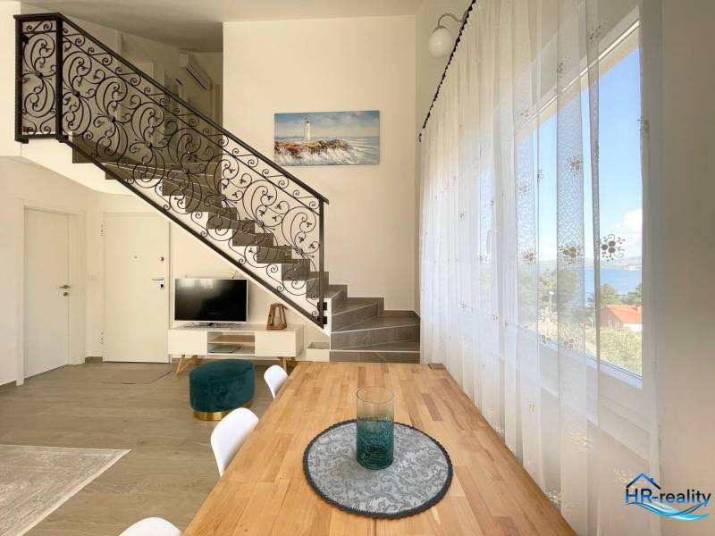 Rekreační apartmán s kovaným schodištěm a jídelním stolem, výhled na moře.