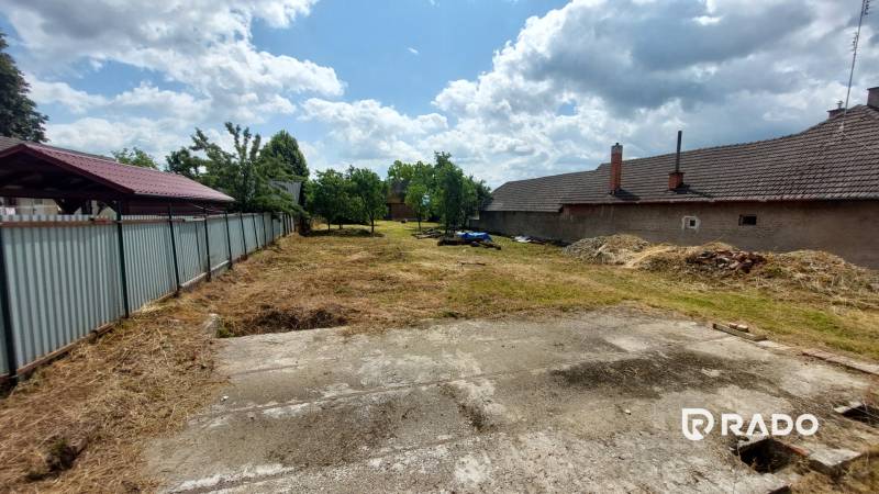 Pozemek v Chocholné-Velčicích na bydlení s travnatou plochou a vedlejšími stavbami.