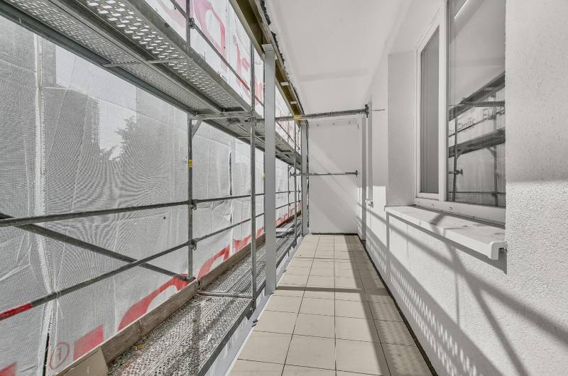 Balkon 4pokojového bytu v rekonstrukci s lešením a dlažbou.