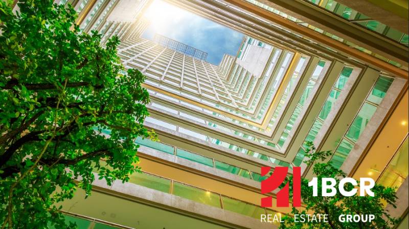 Pohled z atria na výstavbu bytů, s logem 1BCR Real Estate Group.