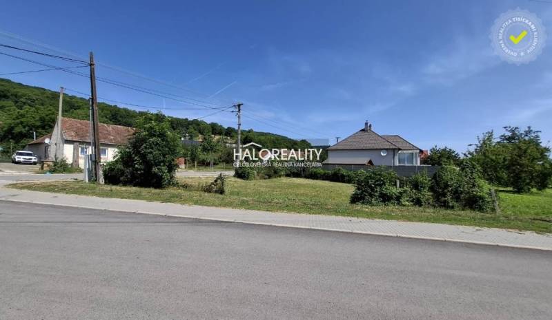 Pozemky - bydlení ve Smolenicích, cesta, domy a zeleň na pozadí.