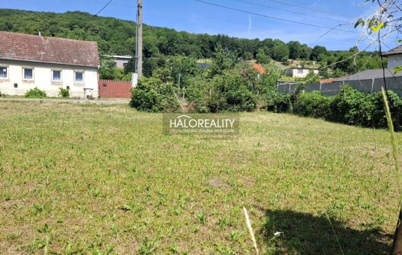 Pozemky - bydlení ve Smolenicích obklopené zelení, s venkovským domem v blízkosti.