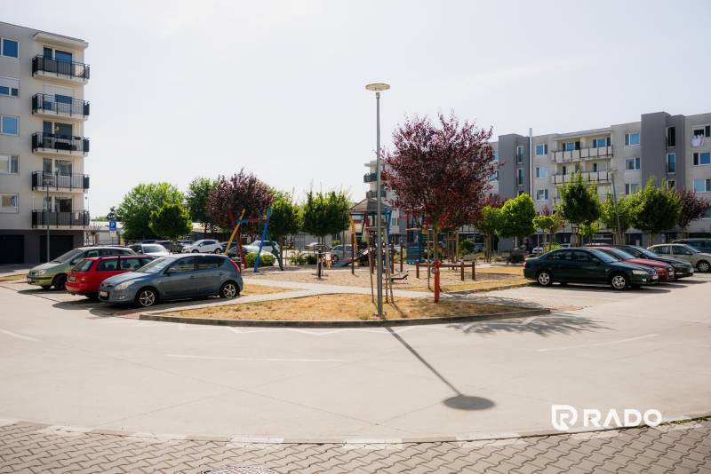 Parkoviště a moderní bytovky v Trenčíně s dětským hřištěm.