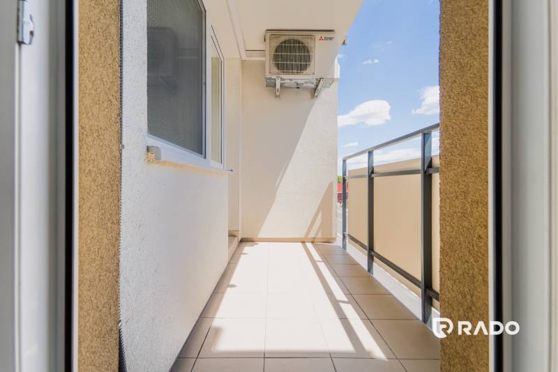 Balkon 2-pokojového bytu v Trenčíně s výhledem na slunečné modré nebe.