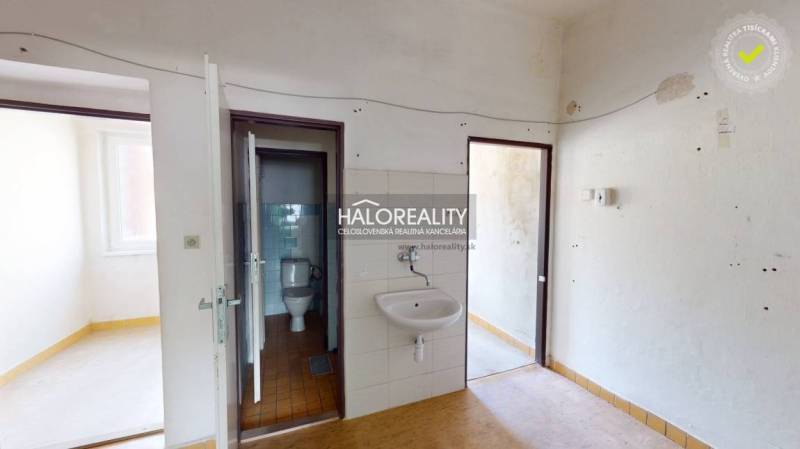 Interiér obchodních prostor s umyvadlem a toaletou, které vyžadují renovaci.