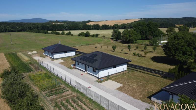 Rodinné domy v Podlužanech s moderními střechami a solárními panely na poli.