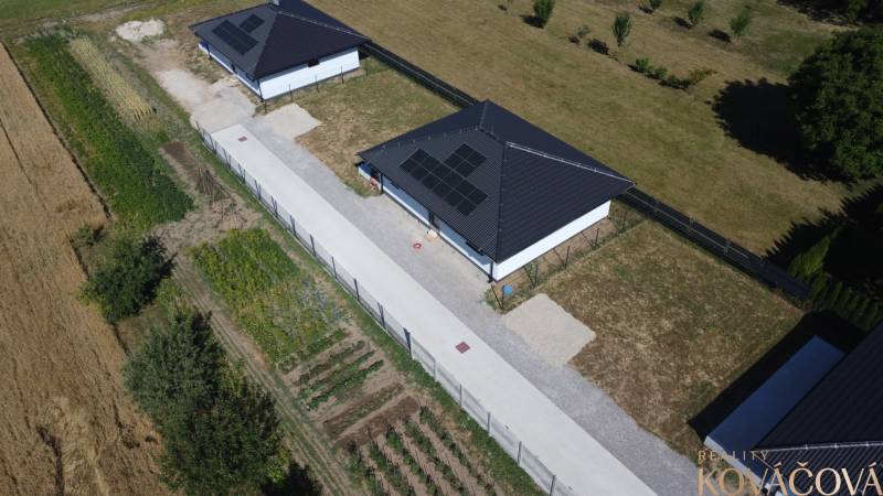Rodinný dům v Podlužanech s fotovoltaickými panely, zahradou a okolními poli.