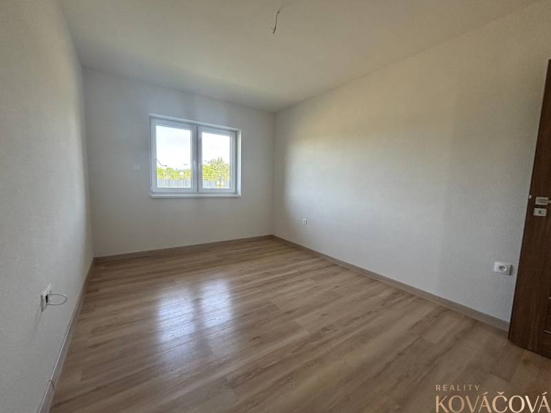 Prázdný pokoj s dřevěnou podlahou a oknem v rodinném domě.