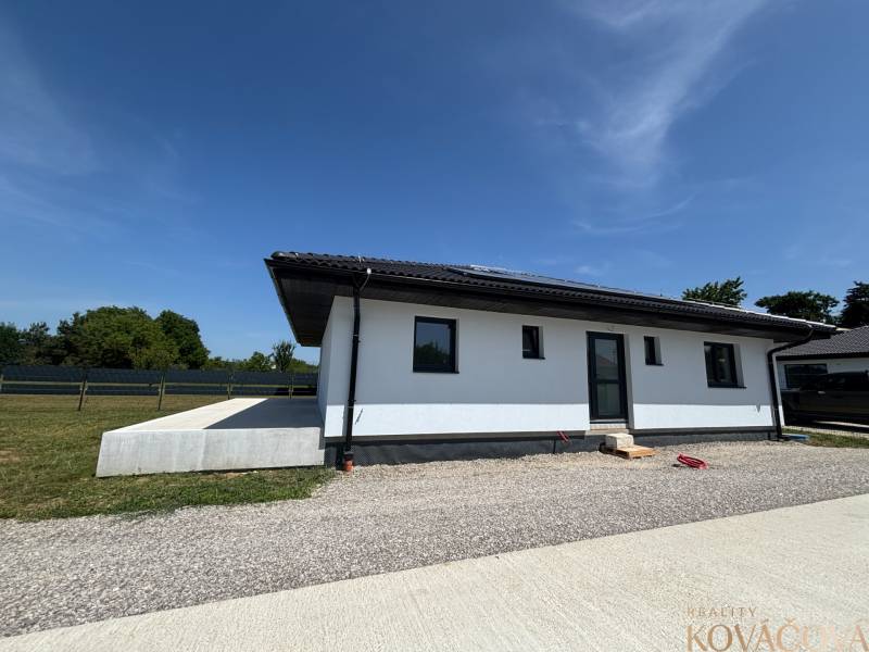 Rodinný dům v Podlužanech s travnatým pozemkem a štěrkovou příjezdovou cestou.