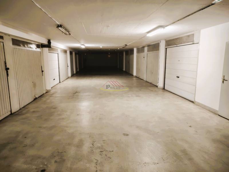 Vnitřní parkovací garáže s uzamykatelnými vraty a betonovou podlahou.
