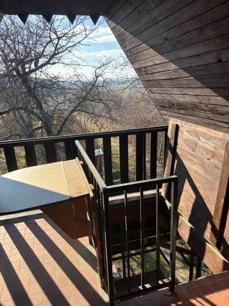 Balkon s dřevěným obkladem a výhledem do přírody, ideální pro rekreační pozemky.
